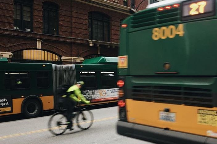 A person biking next to buses