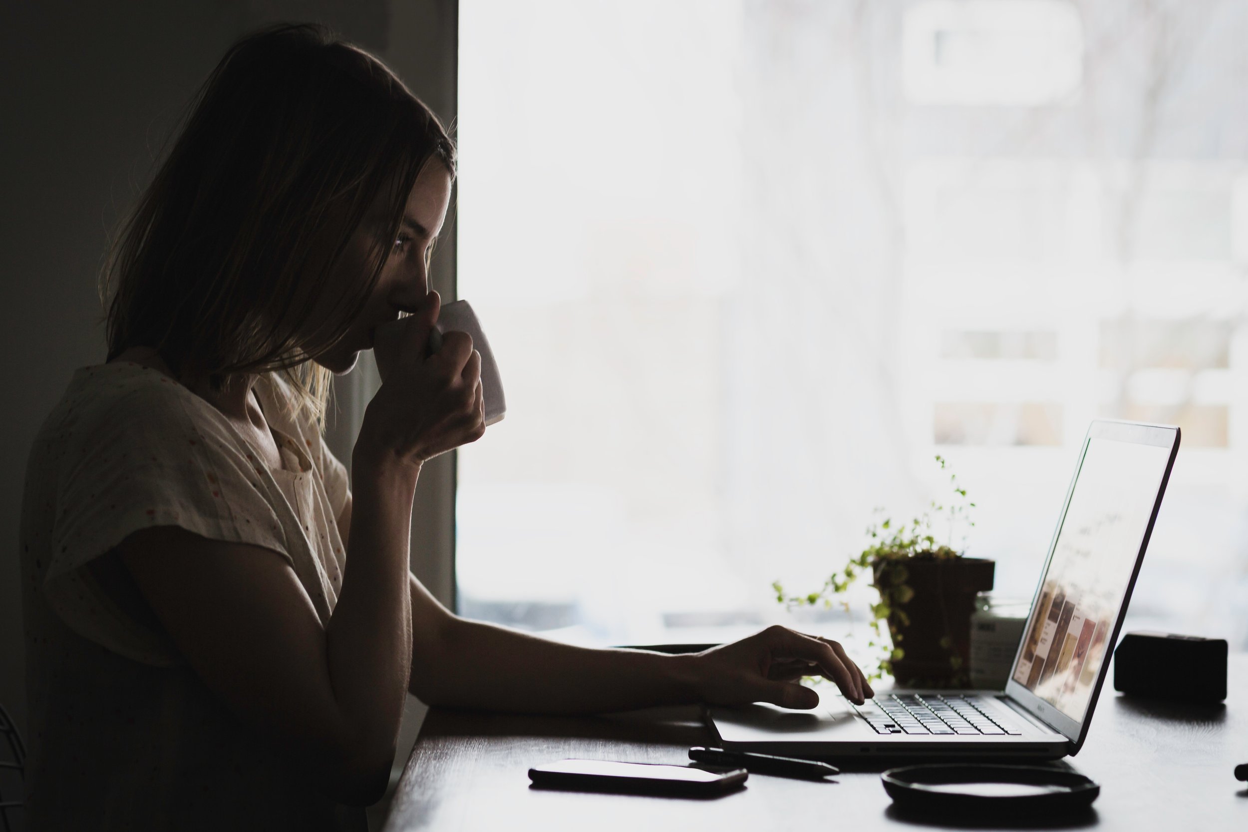 Woman working on a laptop drinking coffee