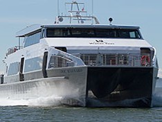Front view of a West Seattle to Downtown catamaran ferry traveling quickly through the water